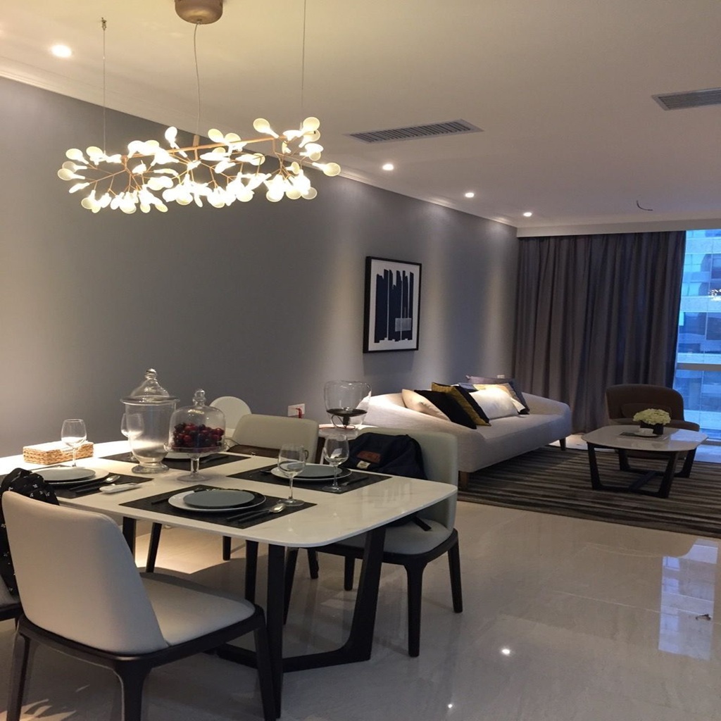 Salón comedor moderno de estilo minimalista con paredes grises, mesa de diseño con sillas blancas, lámpara decorativa contemporánea y zona de estar con sofá claro y decoración elegante